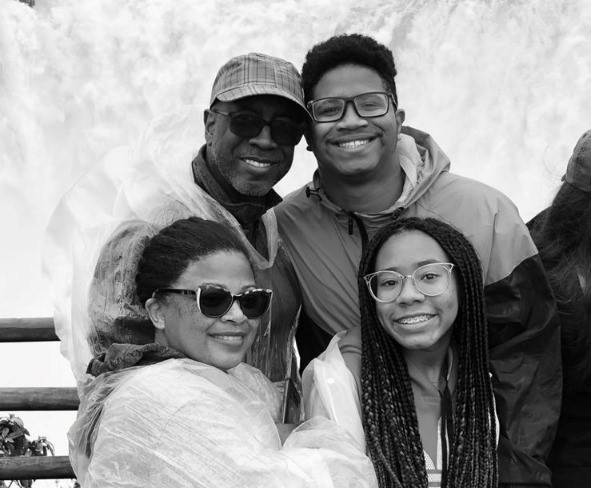A imagem em preto e branca mostra Ronaldo e a família, sendo esposa, a filha e o filho. Todos estão sorrindo para a foto.